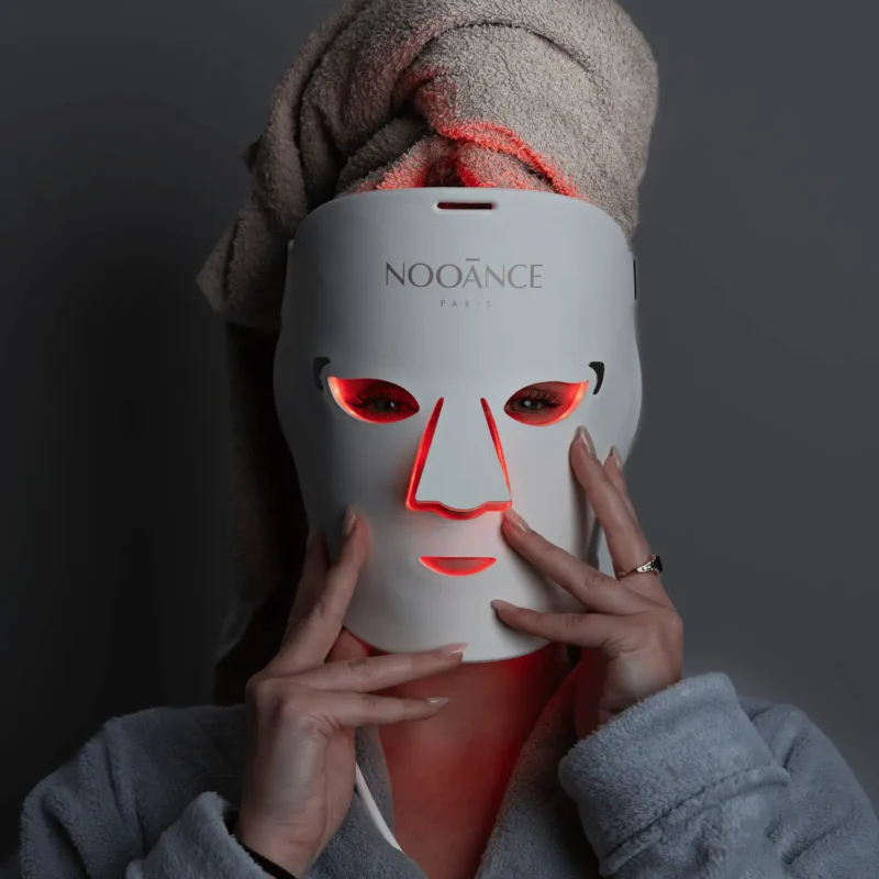 Séance détente à domicile avec le masque LED NOOĀNCE Le Professionnel diffusant une lumière rouge apaisante.